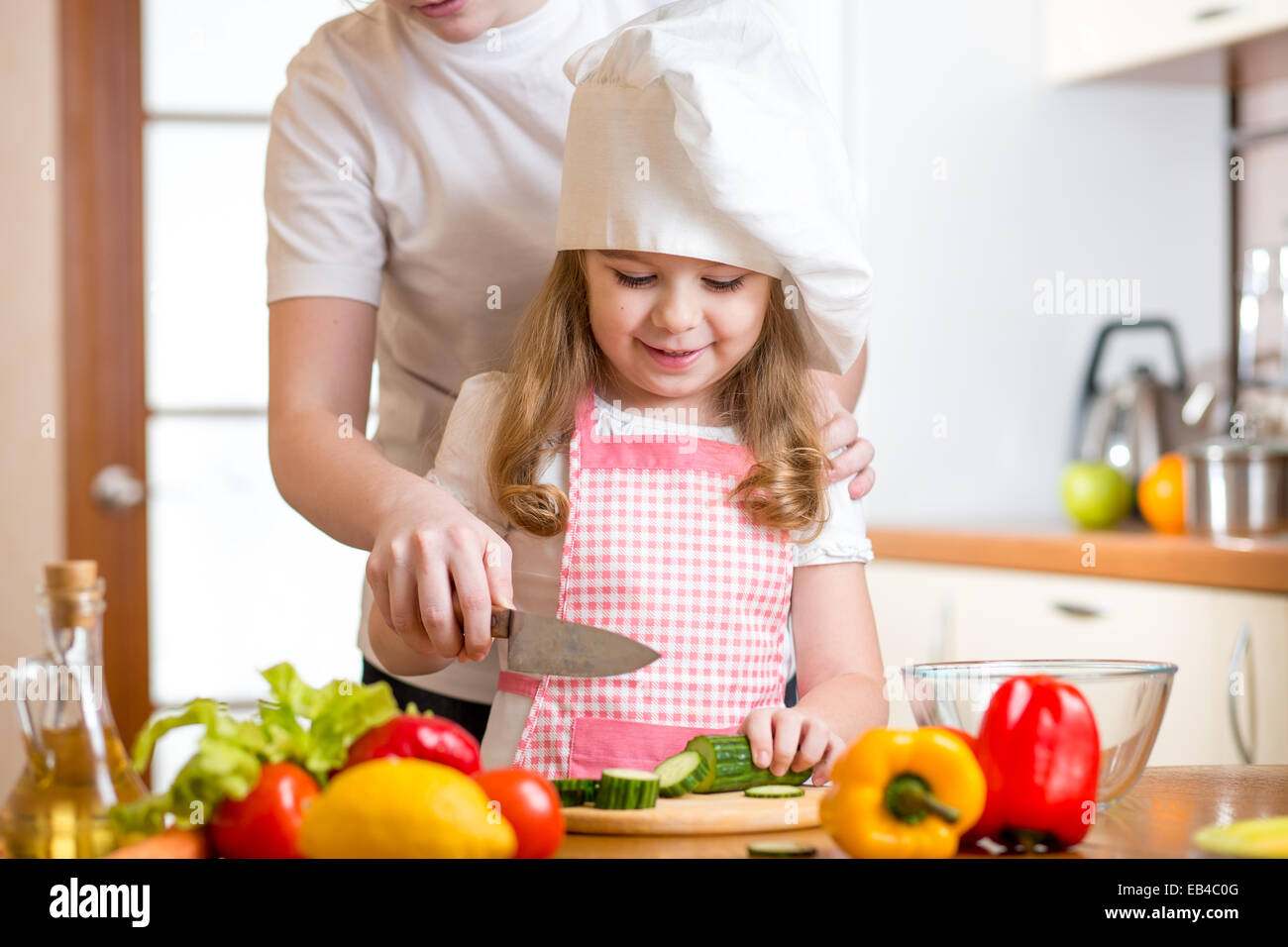 mother and daughter cooking and cutting vegetables on kitchen Stock Photo