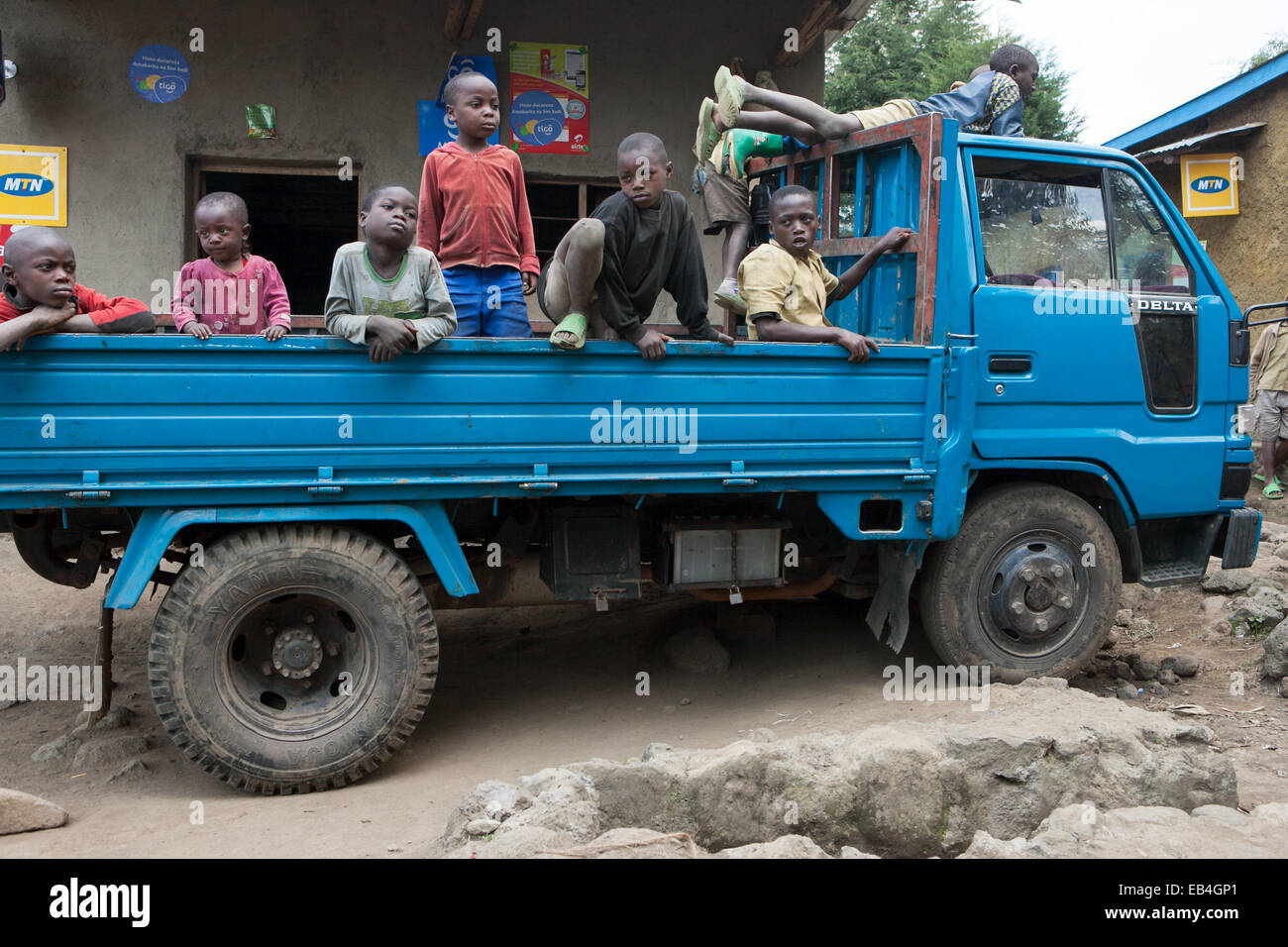 A group of young children sit in and climb on a truck. Stock Photo