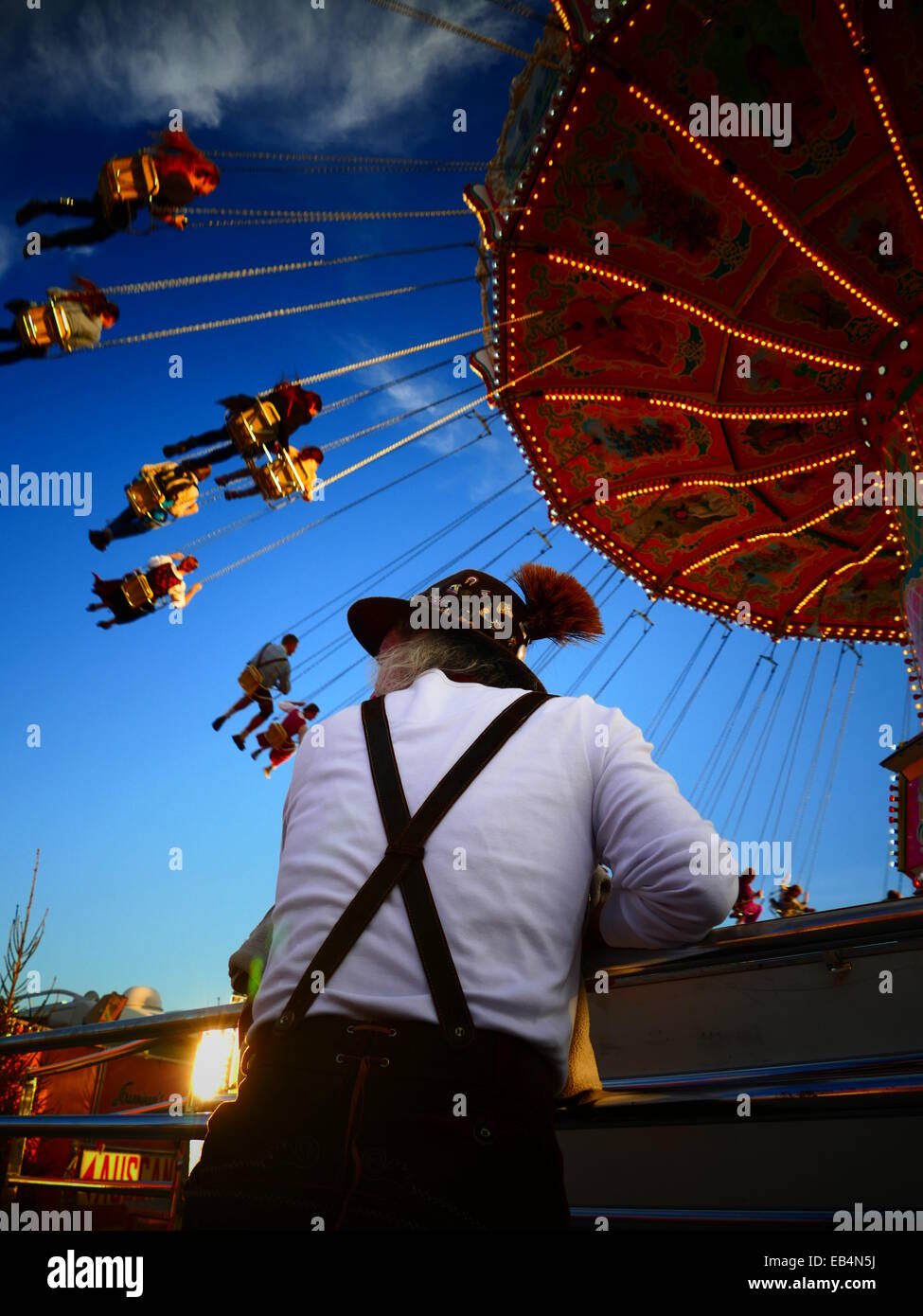 Germany Munich Beer Festival Oktoberfest Octoberfest Fairground 2014 German Man with Lederhosen Costume in front Carousel Stock Photo