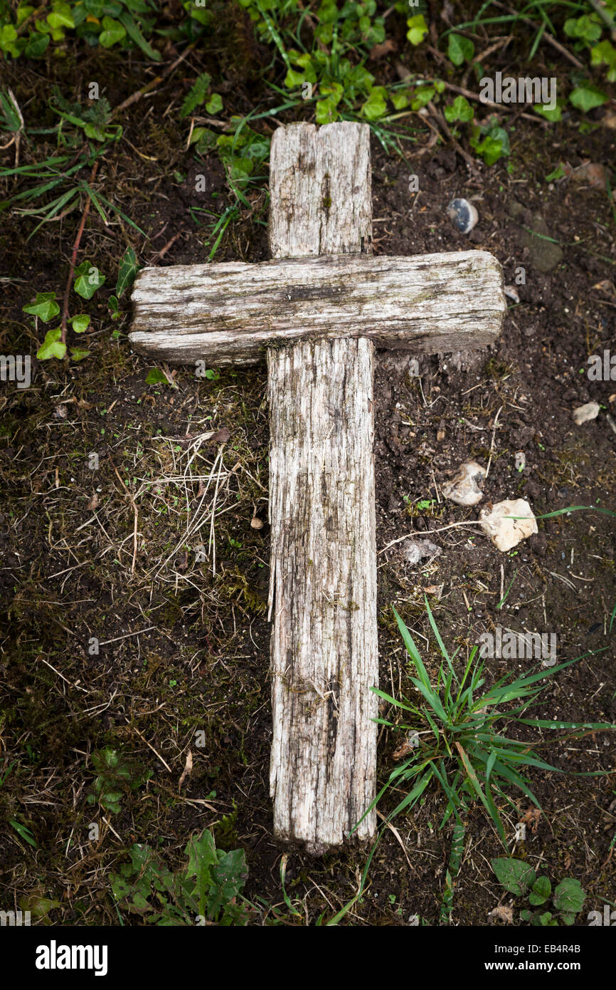 Old wooden cross laid on ground marking grave Stock Photo