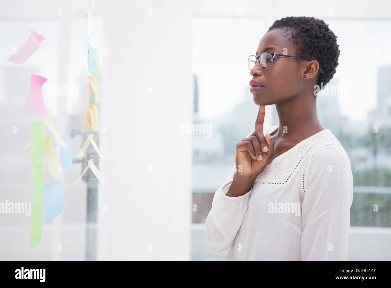 Thoughtful businesswoman looking at sticky notes on window Stock Photo ...