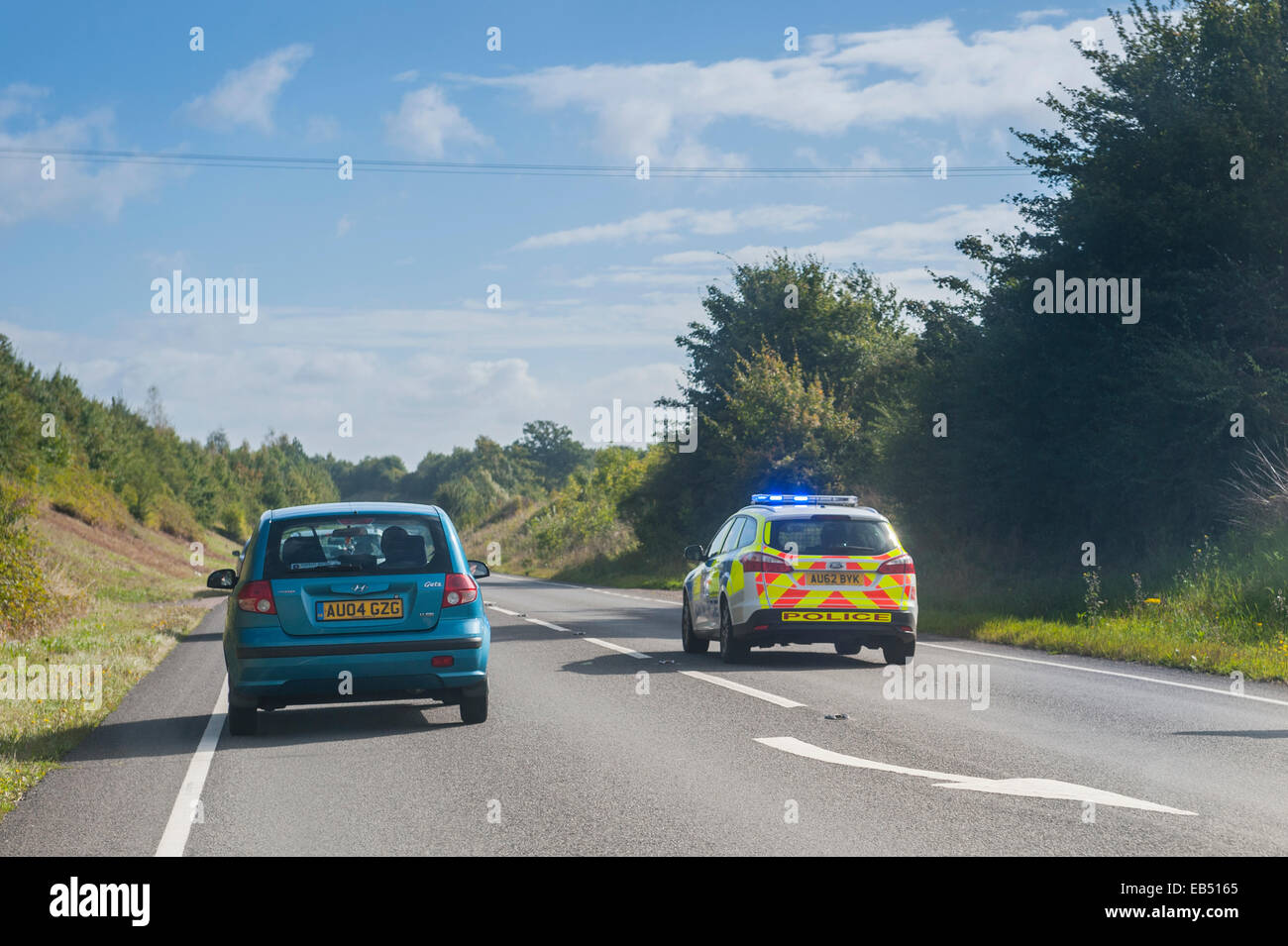 A police car overtakes traffic with emergency blue lights flashing on a