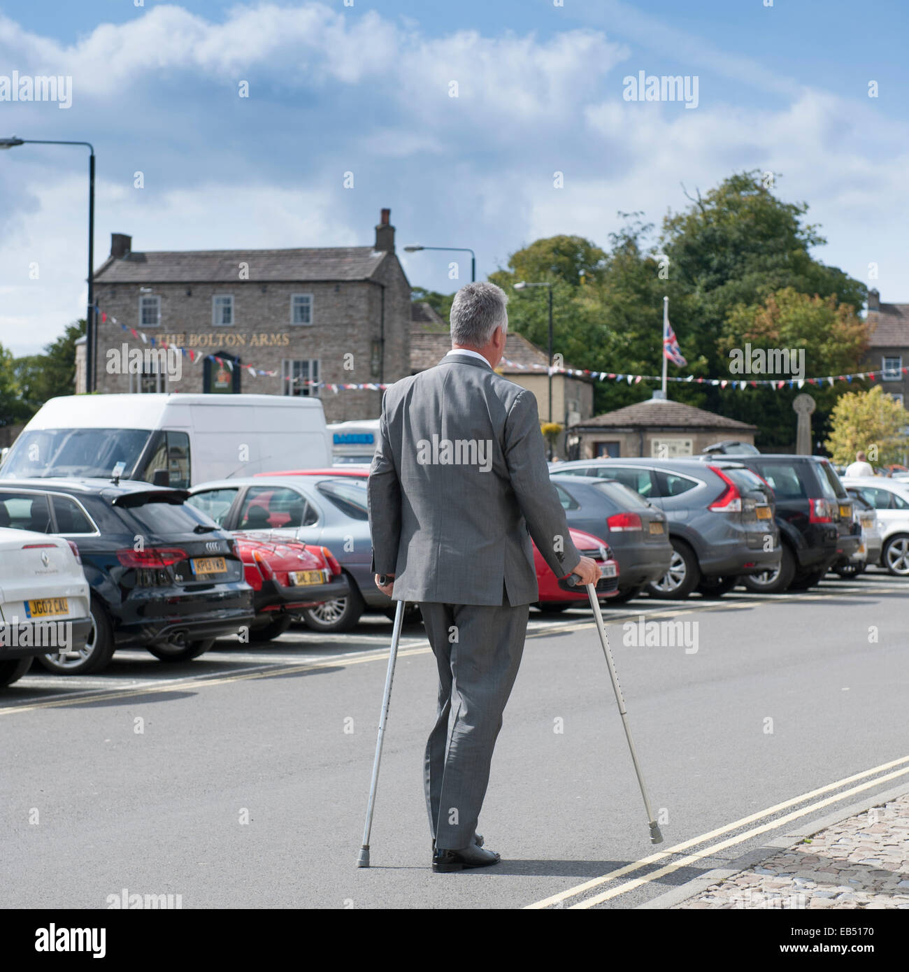 A man walks aided by 2 walking sticks in the Uk Stock Photo - Alamy