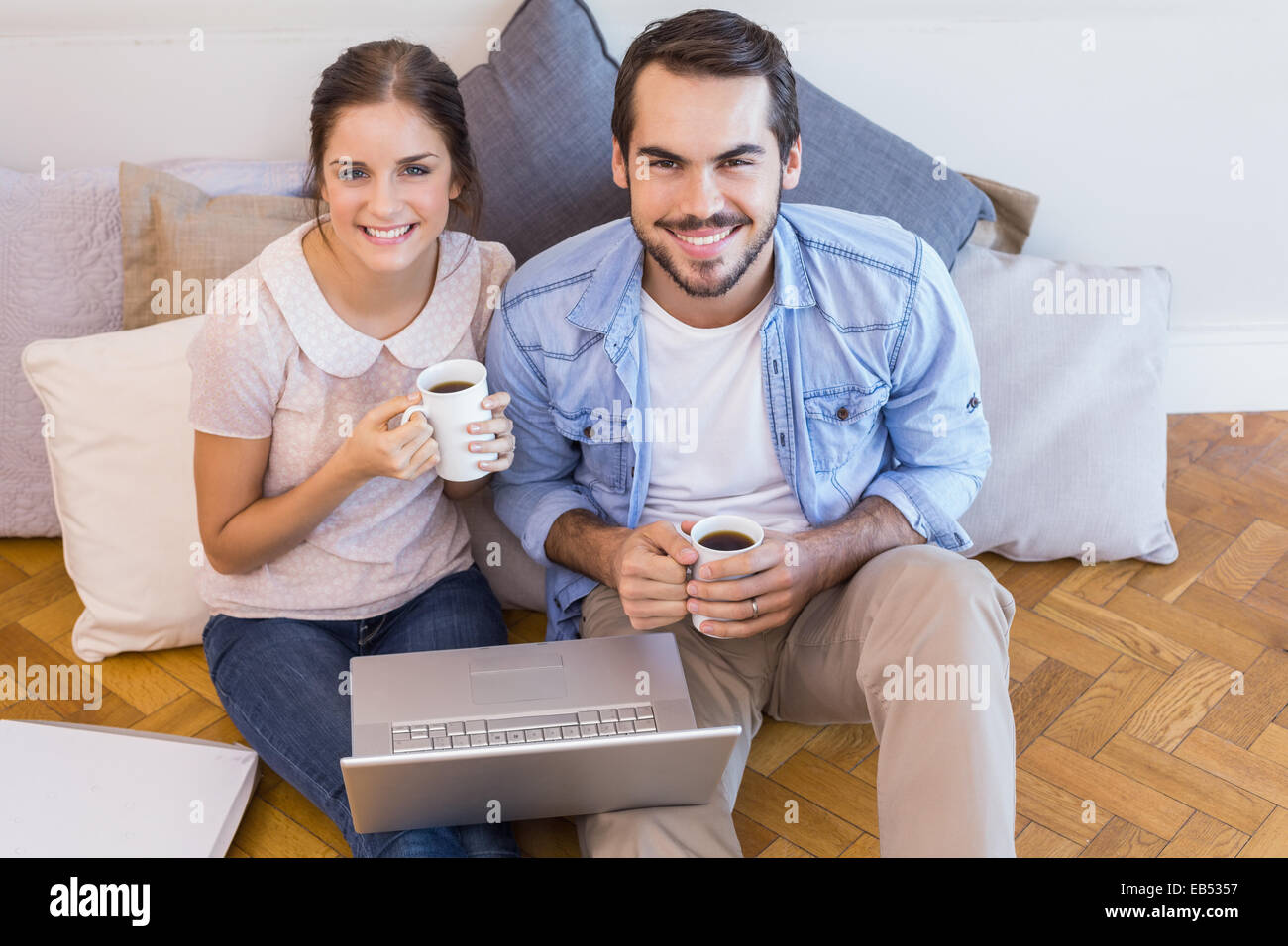 Cute couple sitting on floor using laptop Stock Photo - Alamy