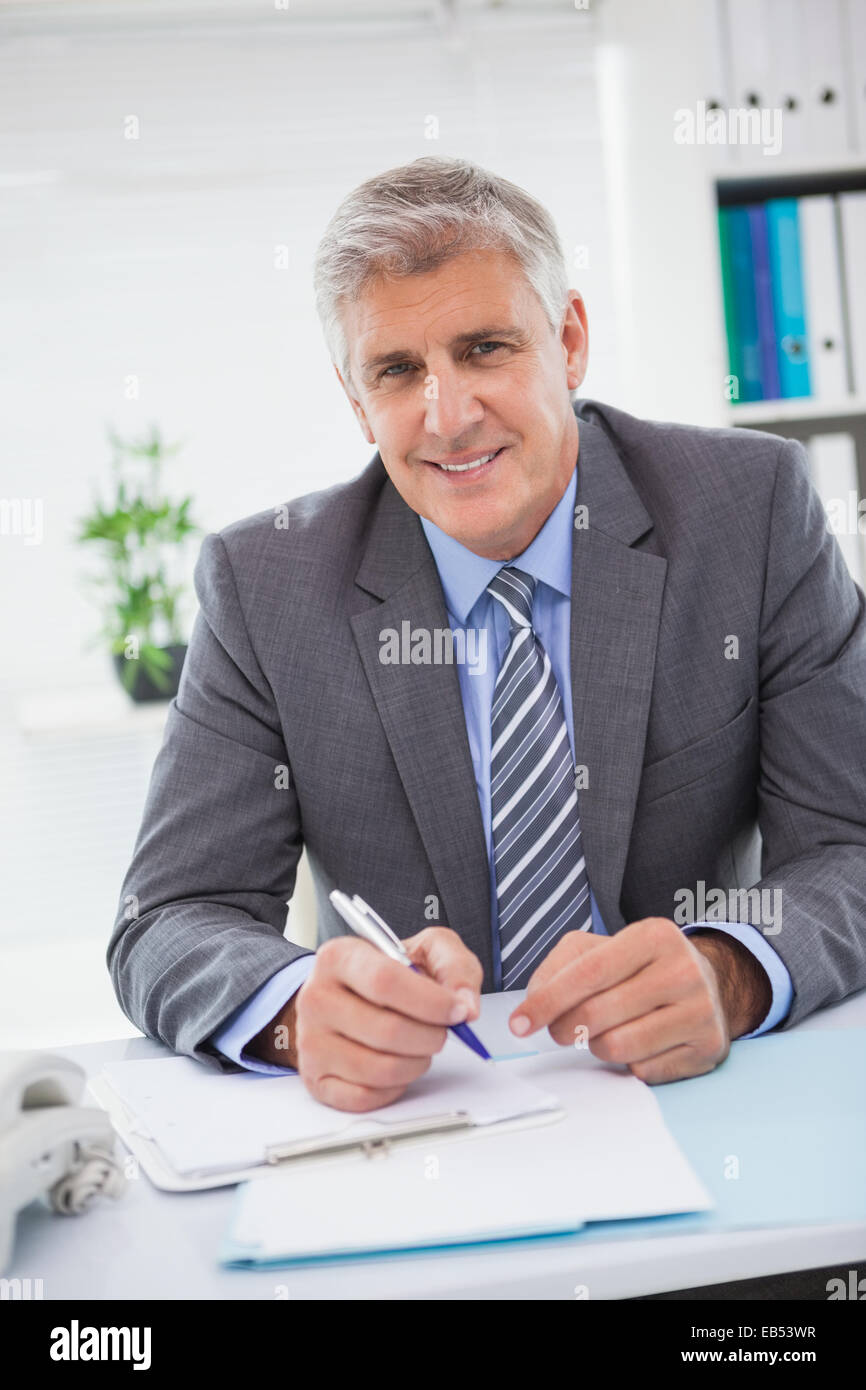 Smiling businessman writing on clipboard Stock Photo - Alamy