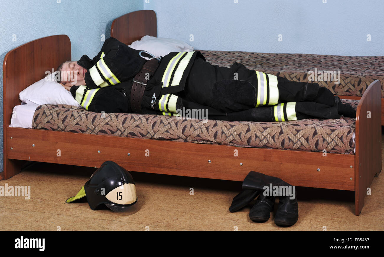 Firefighter sleeping dressed in Bunker gear on the bed Stock Photo