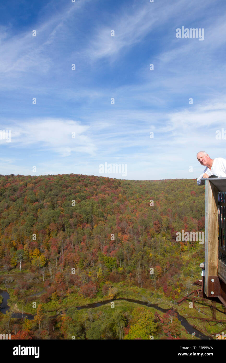 Man on observation platform admiring fall foliage in river valley Stock Photo
