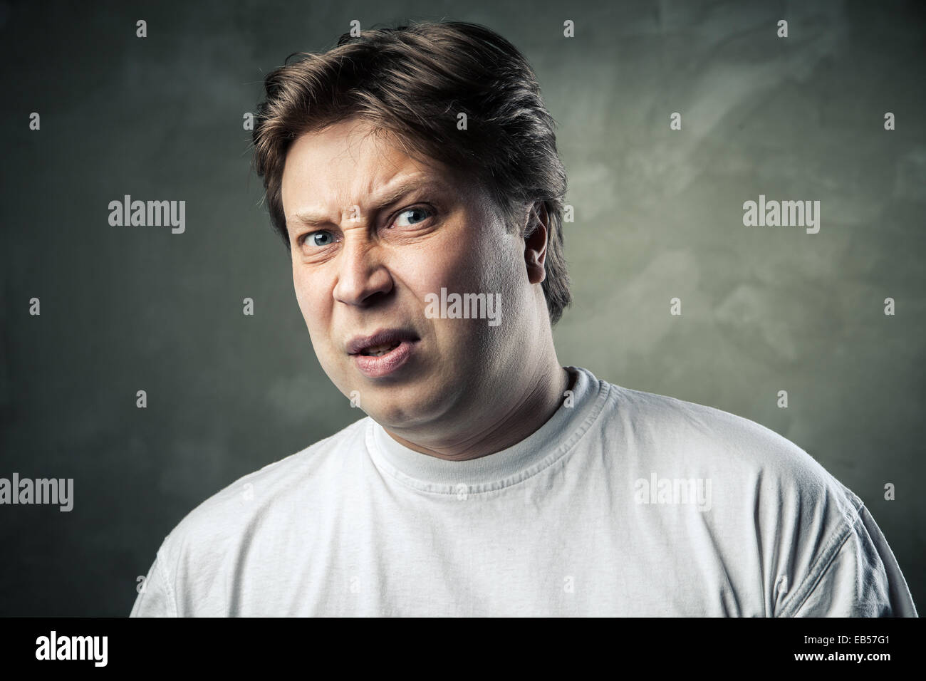 Man with disgusted expression over dark grey background Stock Photo