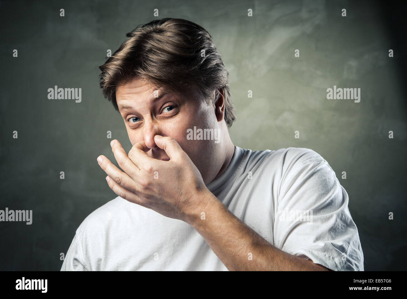 Man with disgusted expression closing his nostrils with his fingers Stock Photo