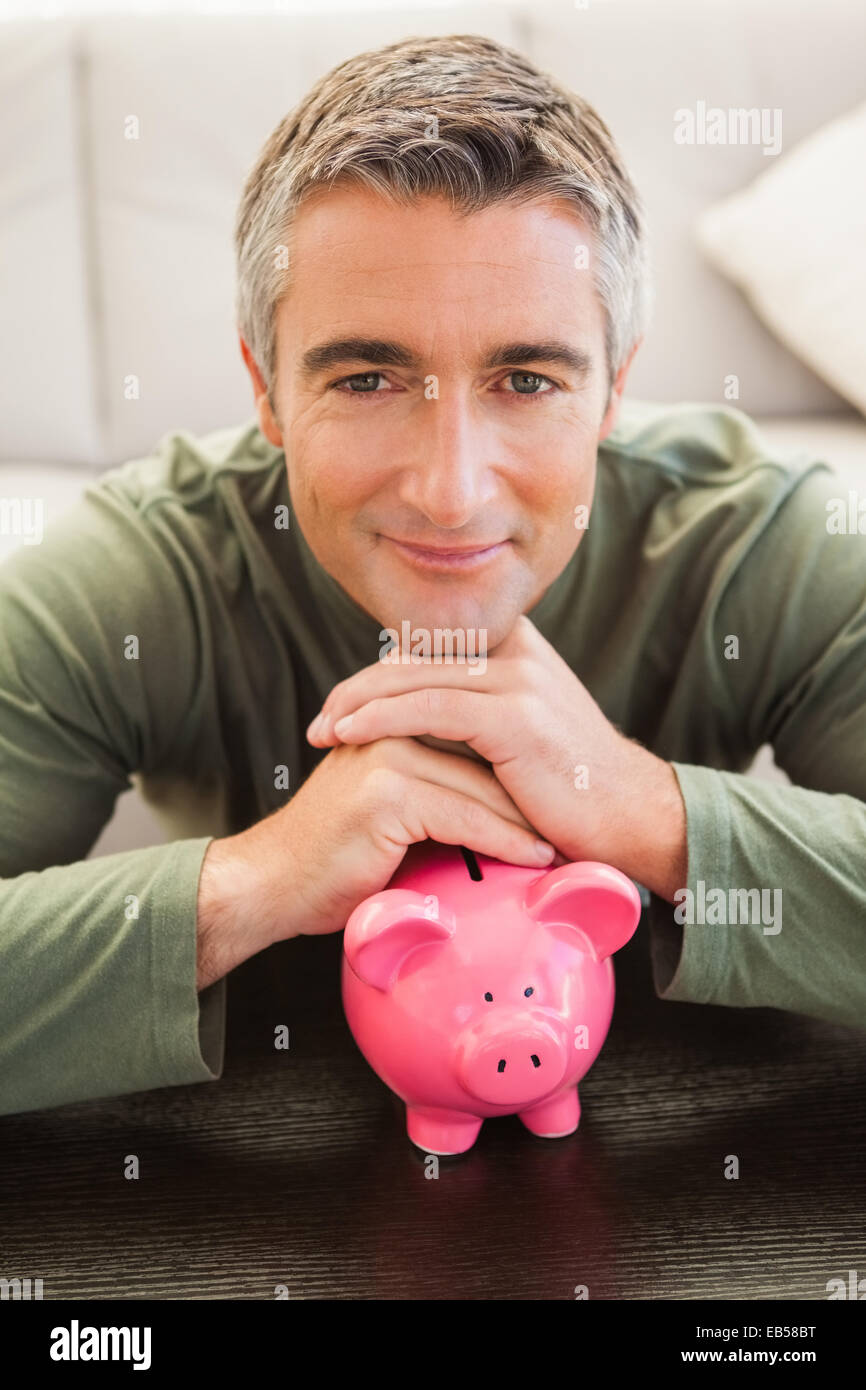 Smiling casual man resting head on piggy bank Stock Photo - Alamy