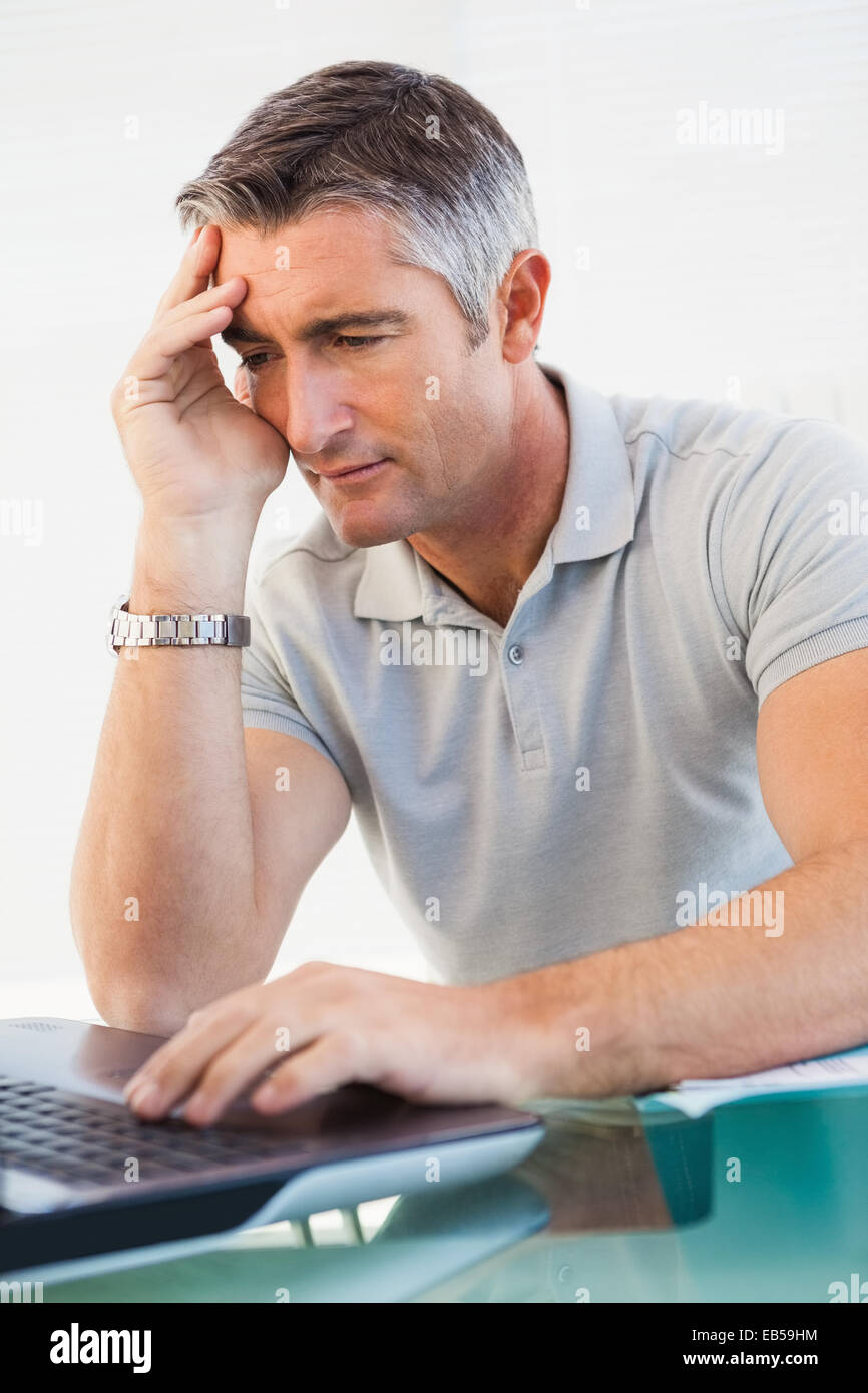 Tired man sitting and using his laptop Stock Photo - Alamy