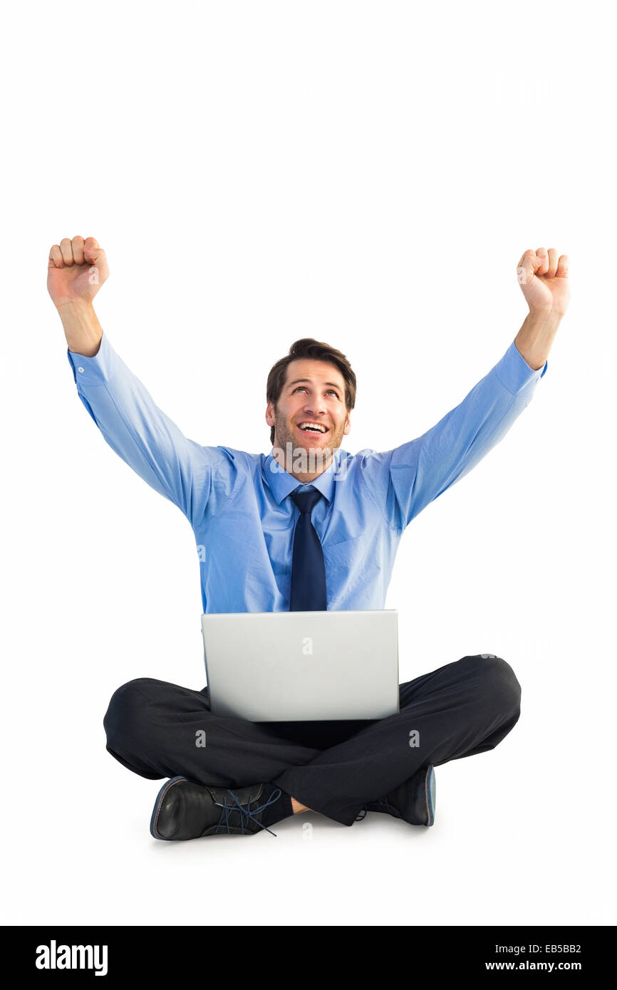 Businessman cheering with laptop sitting on floor Stock Photo - Alamy