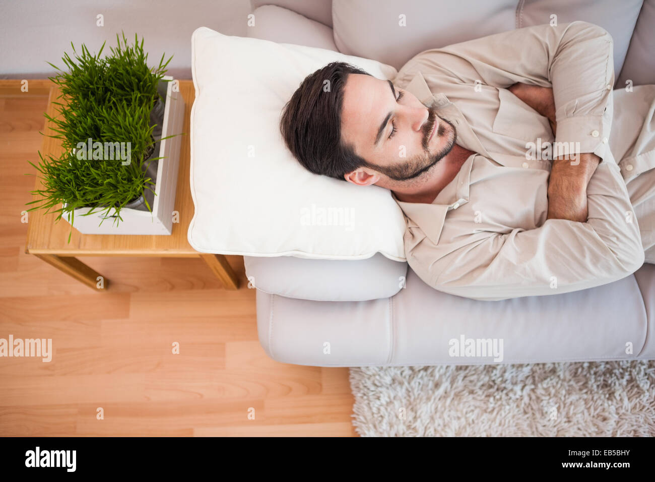 Man sleeping on the couch with arms crossed Stock Photo