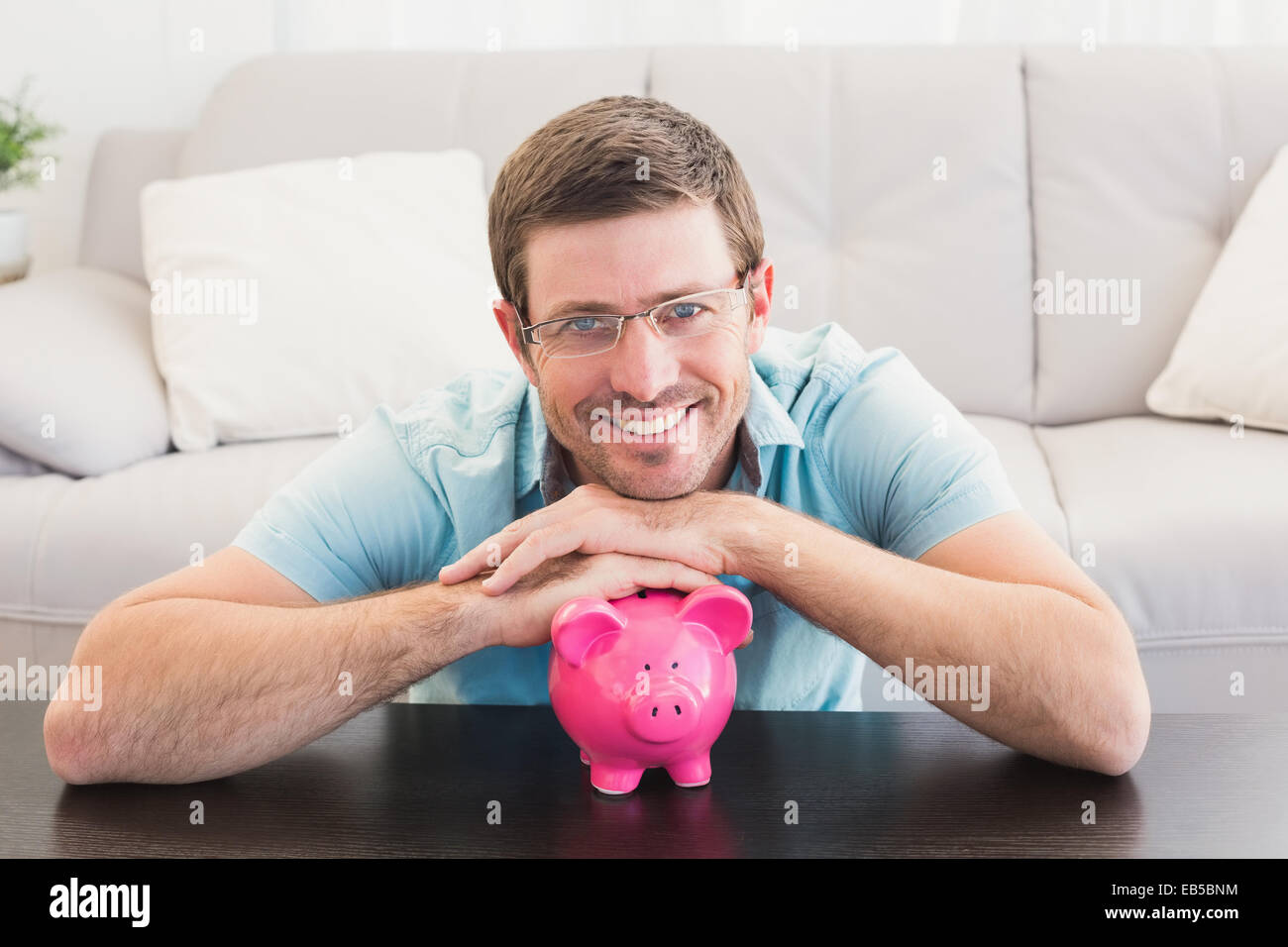 Smiling man with a piggy bank Stock Photo - Alamy