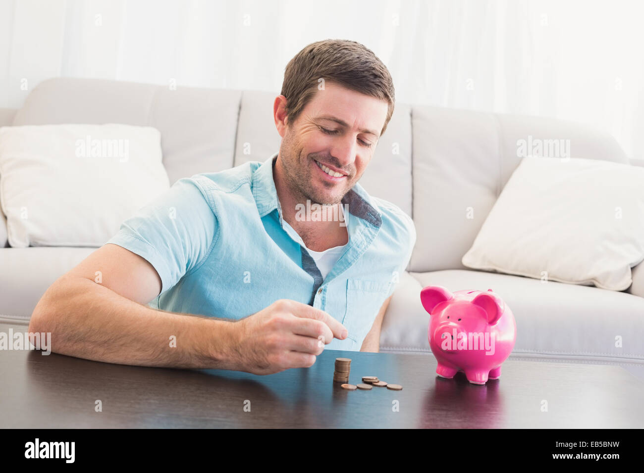 A man putting coins in piggy bank Stock Photo - Alamy