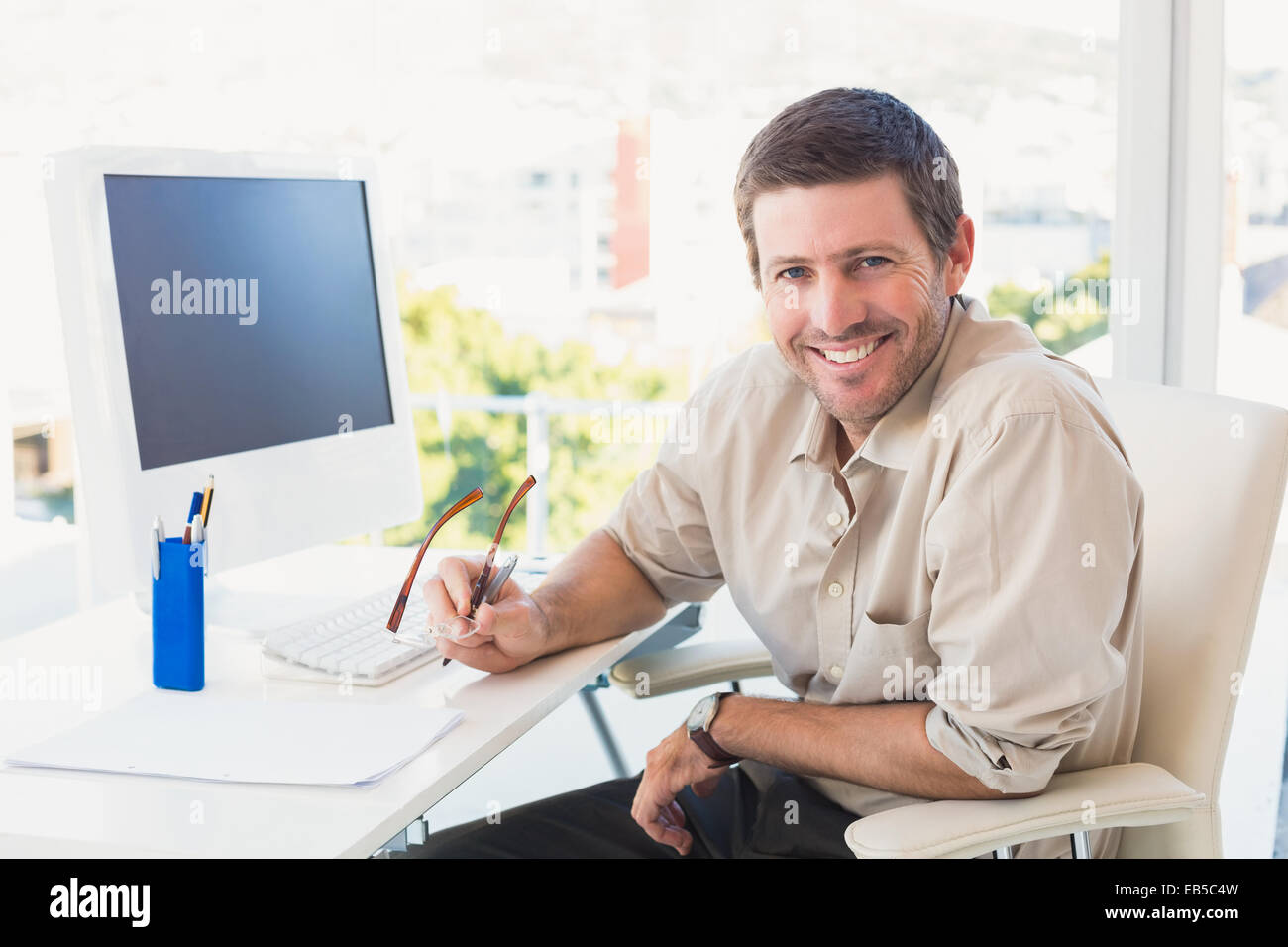 Smiling casual businessman at his desk Stock Photo - Alamy