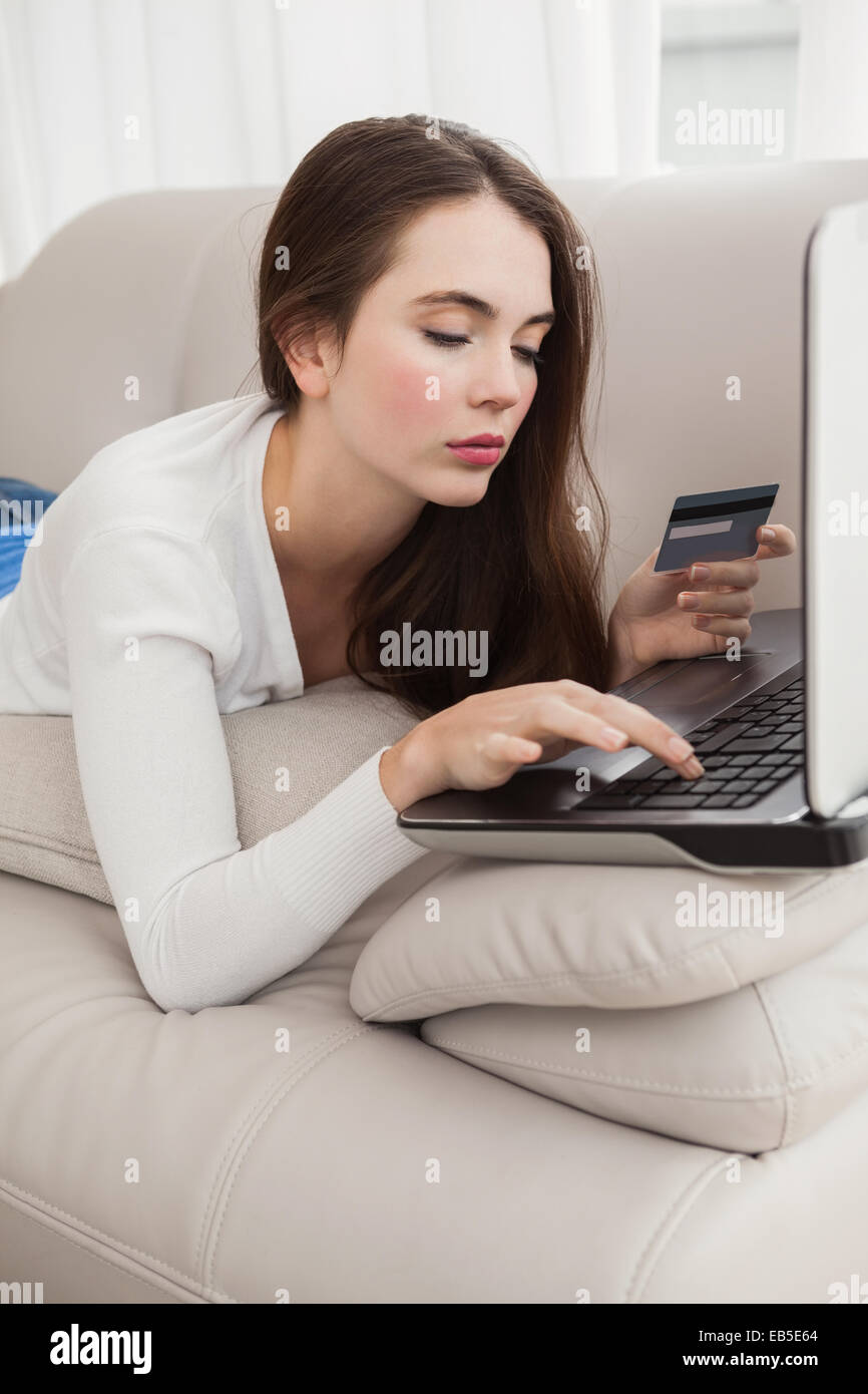 Pretty brunette shopping online on couch Stock Photo - Alamy