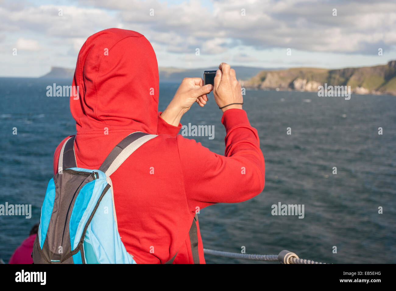 Middle age man taking a picture of the cliff at Carrick a rede in North Antrim, Northern Ireland Stock Photo