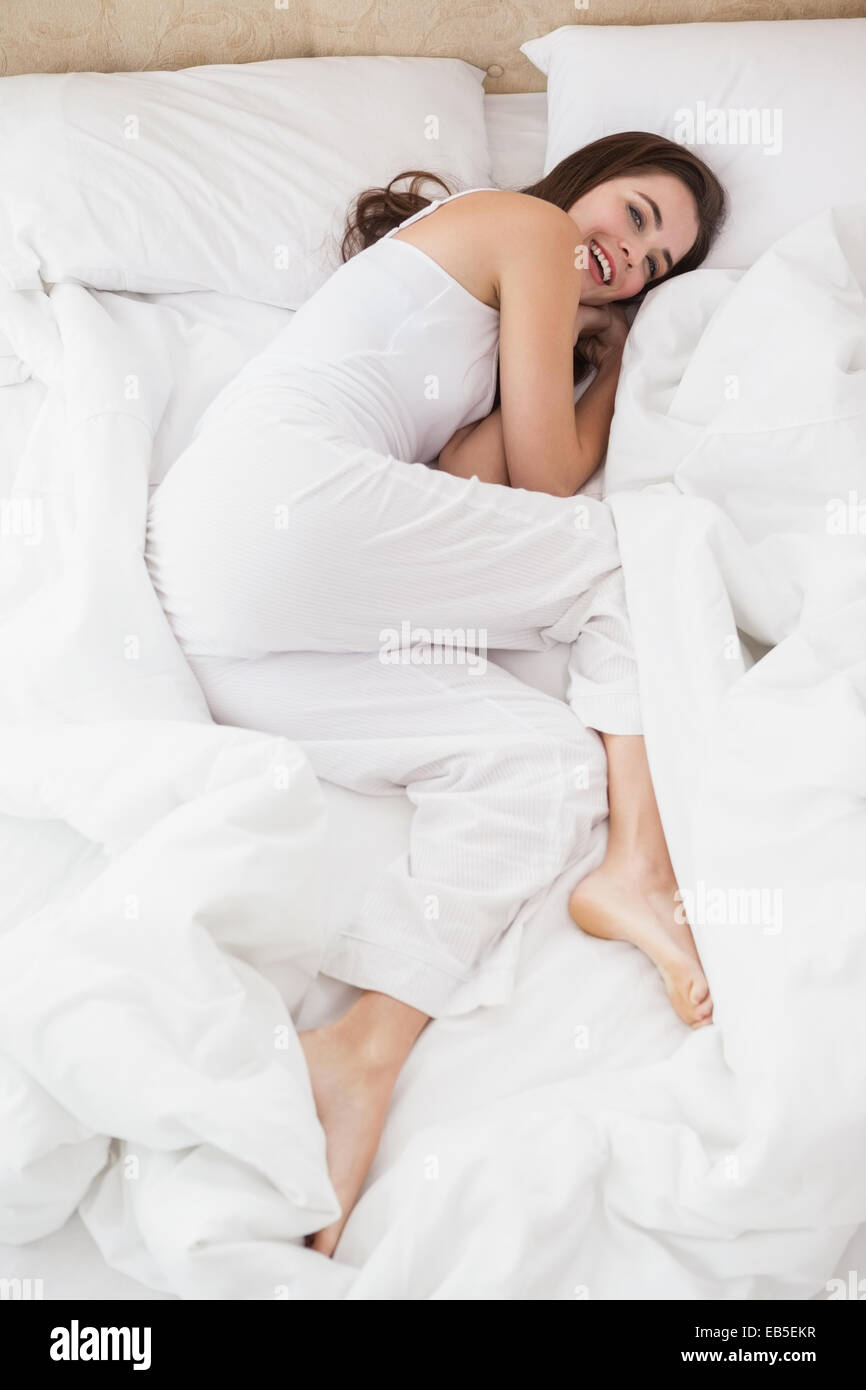 Pretty brunette lying in bed smiling at camera Stock Photo - Alamy