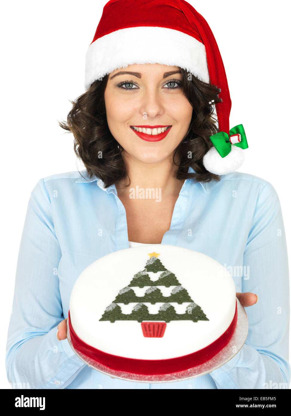 Confident Young Woman Wearing A Red Santa Hat Holding A Rich Iced Christmas Fruit Cake Isolated Against A White Background With A Clipping Path Stock Photo