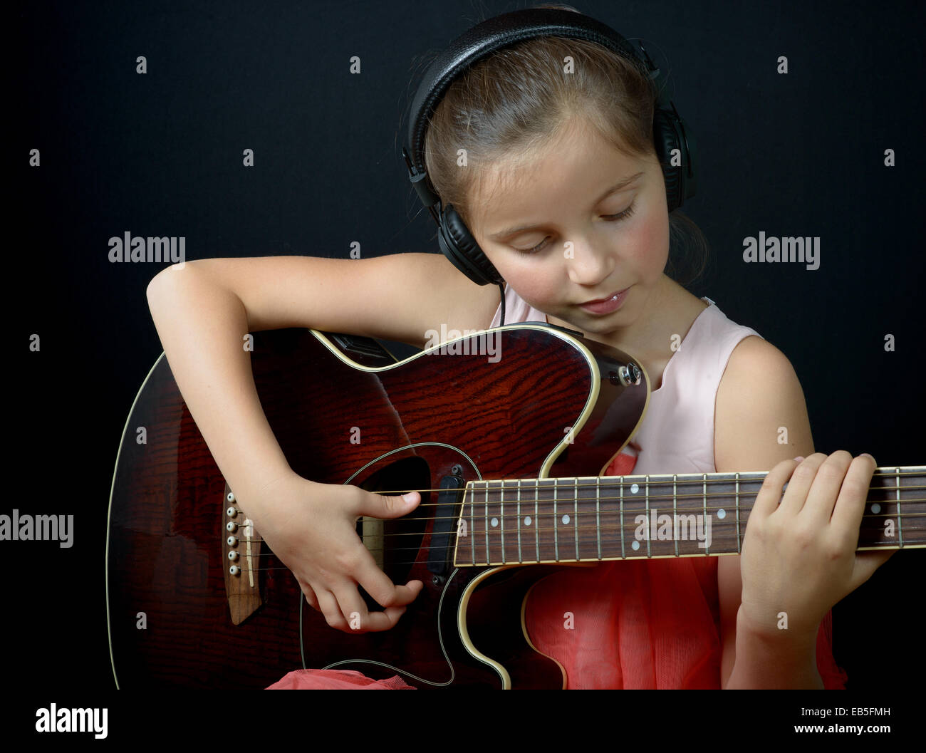 a pretty little girl whit headphones playing guitar Stock Photo