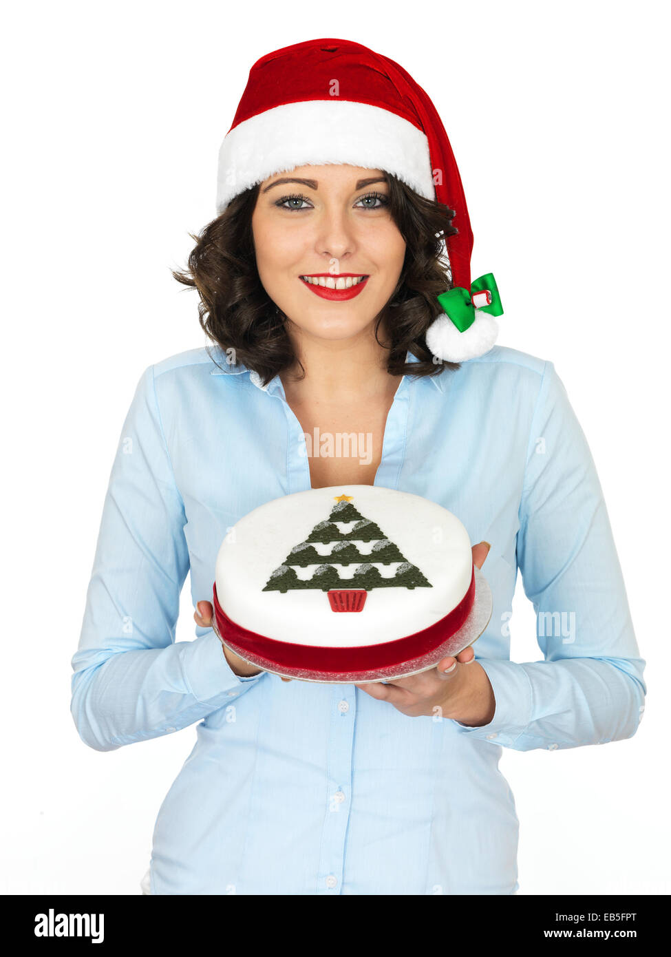 Confident Young Woman Wearing A Red Santa Hat Holding A Rich Iced Christmas Fruit Cake Isolated Against A White Background With A Clipping Path Stock Photo