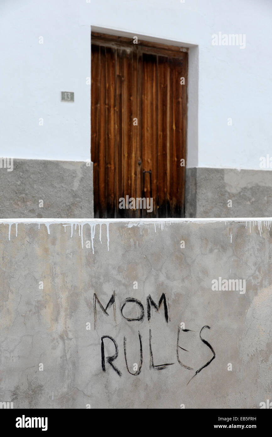 Graffiti "Mom Rules" on gray wall in front of closed door Stock Photo