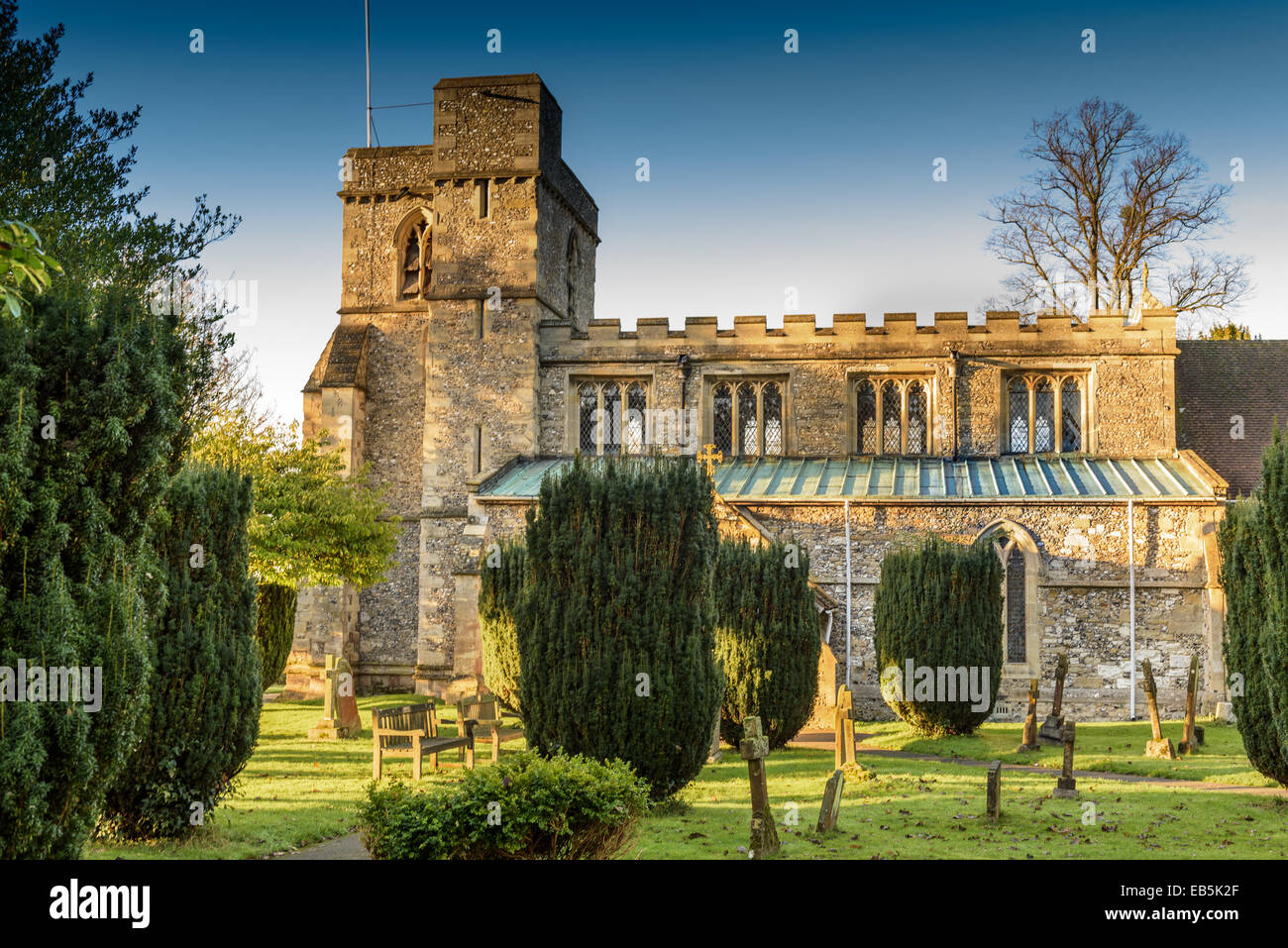 Monks Risborough Church in the late afternoon sun with yew trees and gravestones Stock Photo
