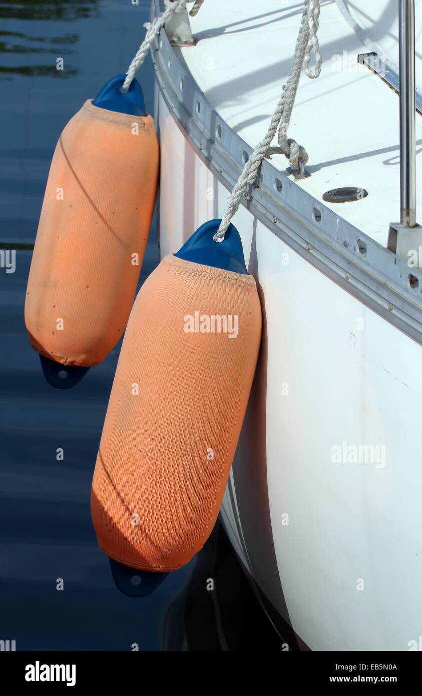 Close up on two orange fenders aside of a white boat Stock Photo