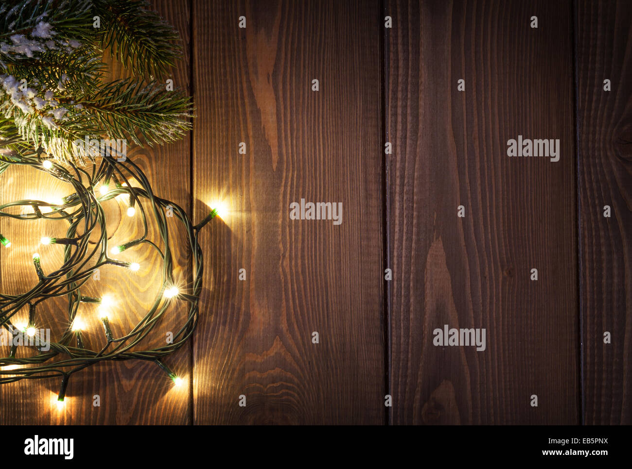 Christmas lights and snow fir tree over wooden background with copy ...