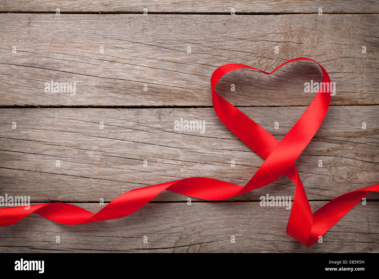 Valentines day heart shaped red ribbon over wooden table background ...
