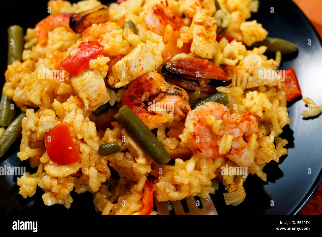 paella with shrimps and mussels on black plate, close-up Stock Photo