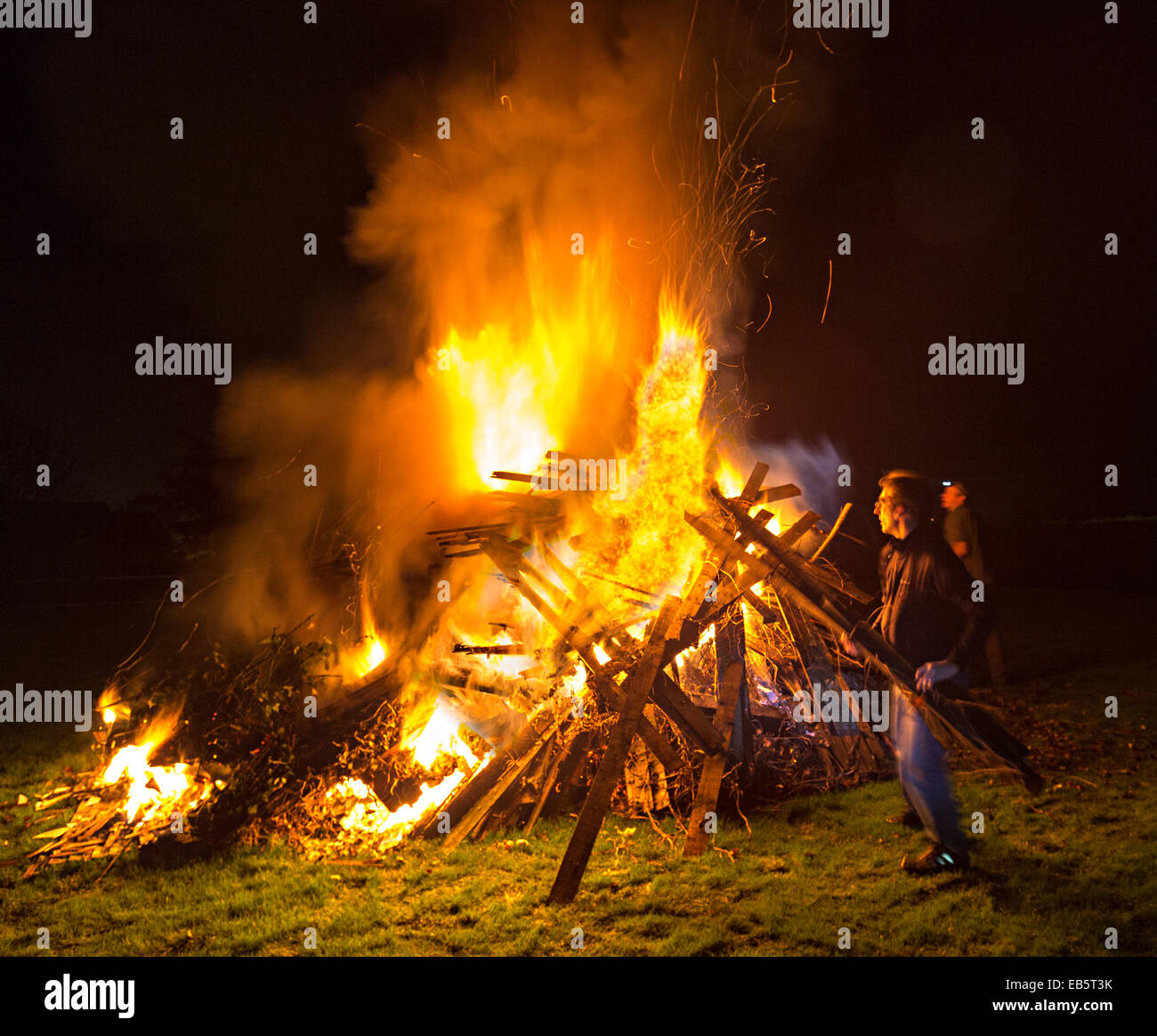 People putting wood onto garden bonfire, UK Stock Photo