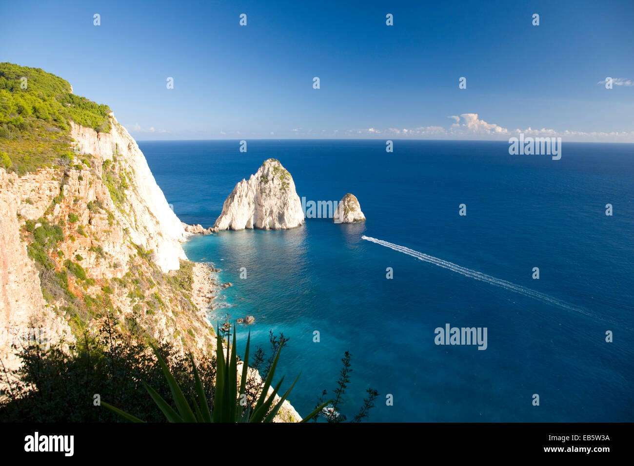 Keri, Zakynthos, Ionian Islands, Greece. View to the Myzithres Rocks from clifftop at Cape Keri, boat speeding across water. Stock Photo