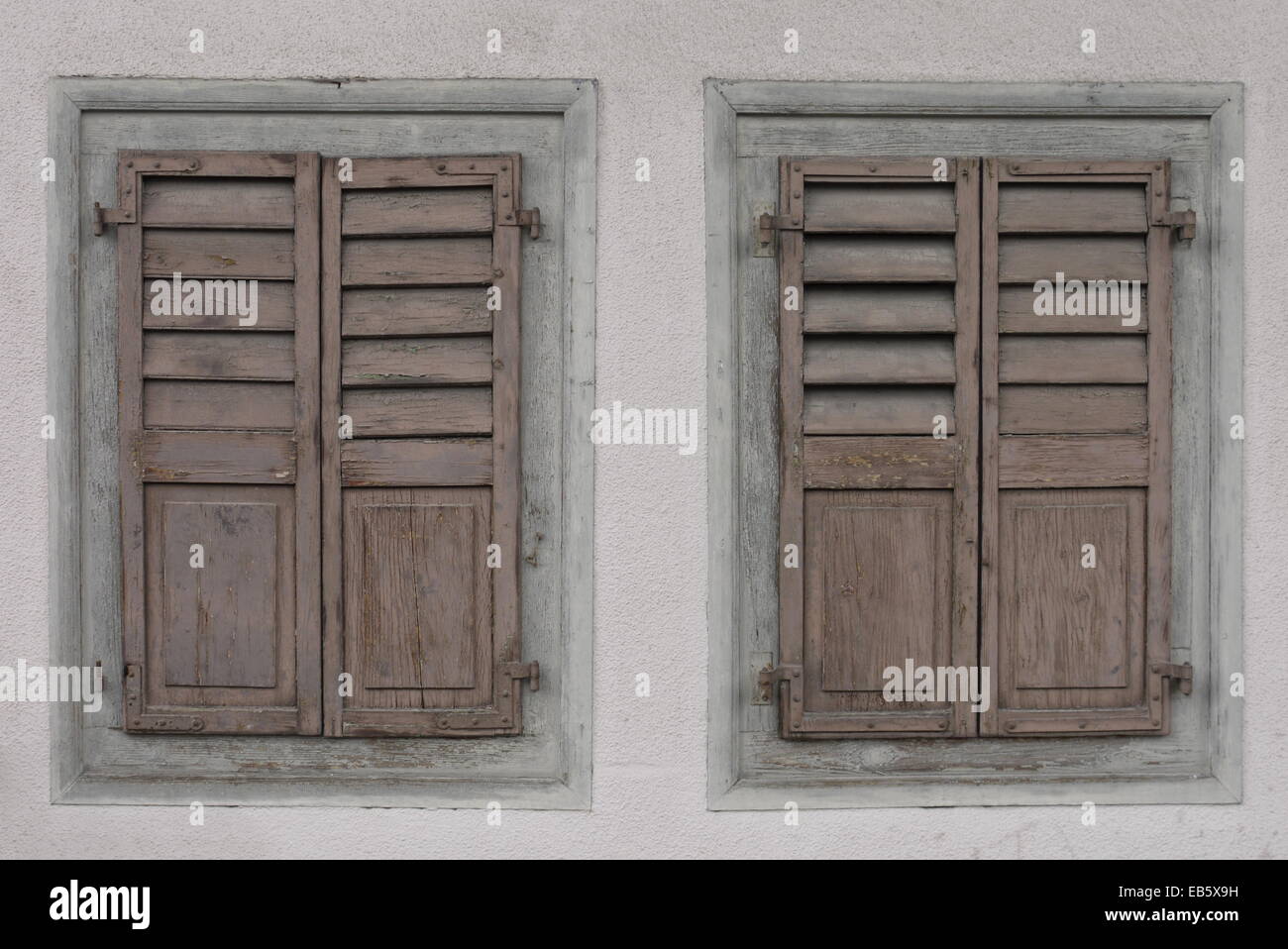 Twins of vintage, outdated pastel wooden shuttered window blinds - Paar alte, verwitterte geschlossene Holz-Fensterläden pastell Stock Photo