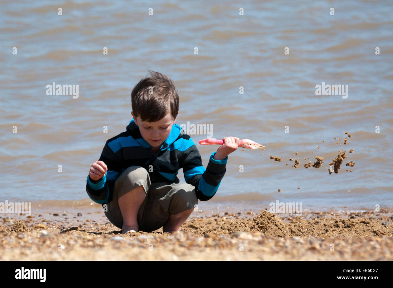 Boy digging on the beach Stock Photo