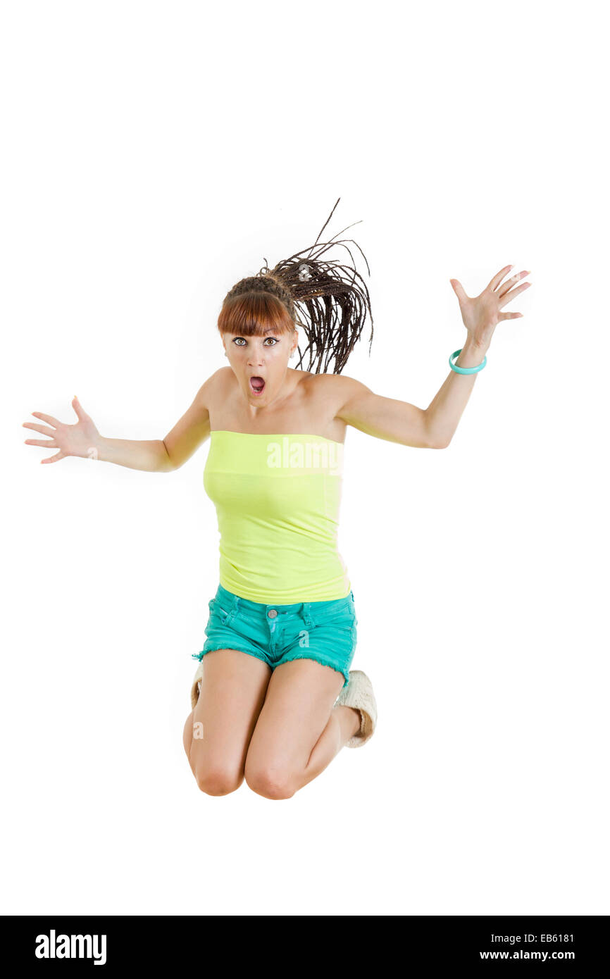 Shocked and surprised beautiful cute young woman or girl in blank green t-shirt and shorts jumps with face expression over white Stock Photo