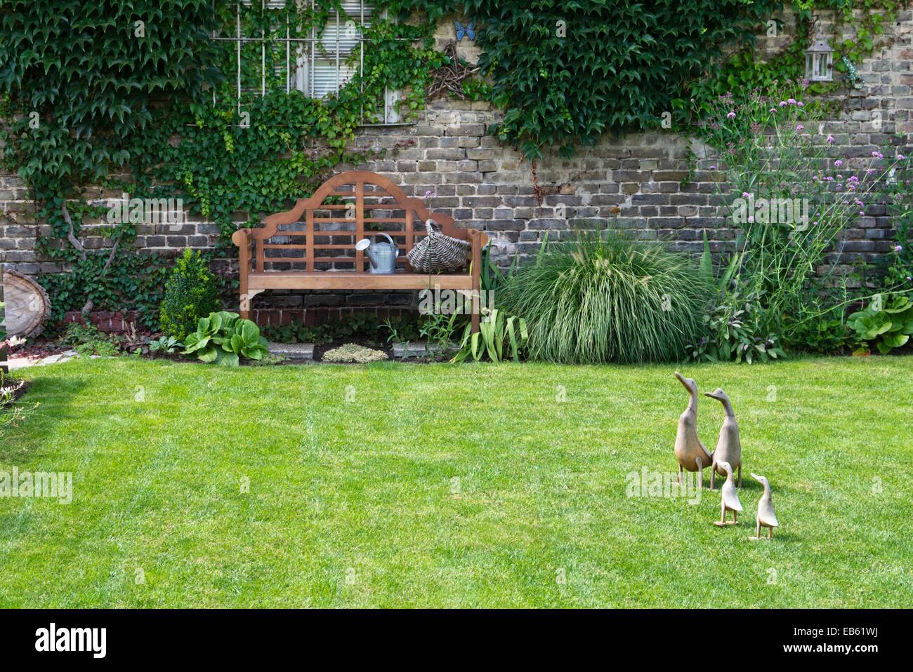 Garden bench in front of a brick wall Stock Photo - Alamy