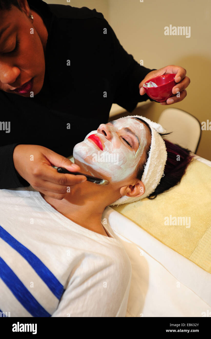 Beauty Salon white woman getting a facial treatment from a black beautician Stock Photo