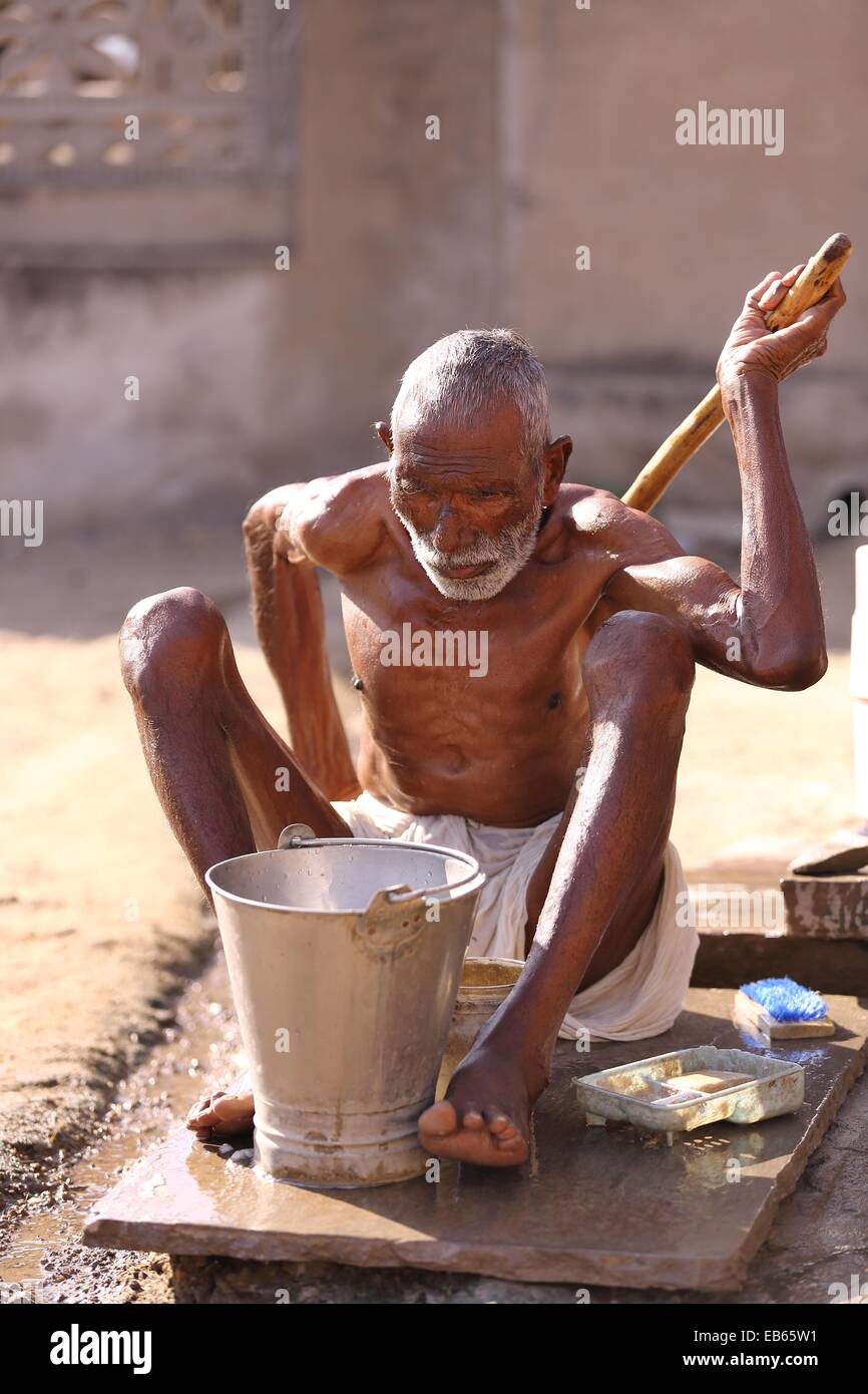 Old Indian man using a stick to wash his back India Stock Photo