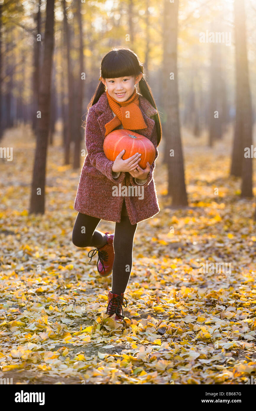 Little girl holding a pumpkin in autumn woods Stock Photo - Alamy