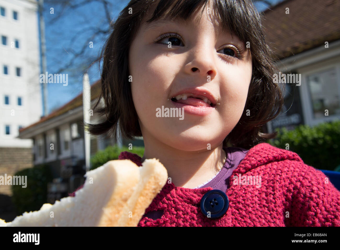 Little girl eating white bread sandwich Stock Photo