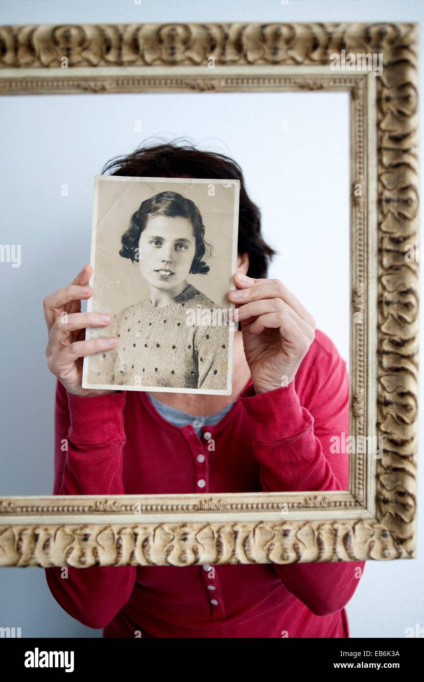 Mujer joven dentro de un marco dorado con retrato antiguo en las manos tapandole la cara Young woman in gold frame with old Stock Photo