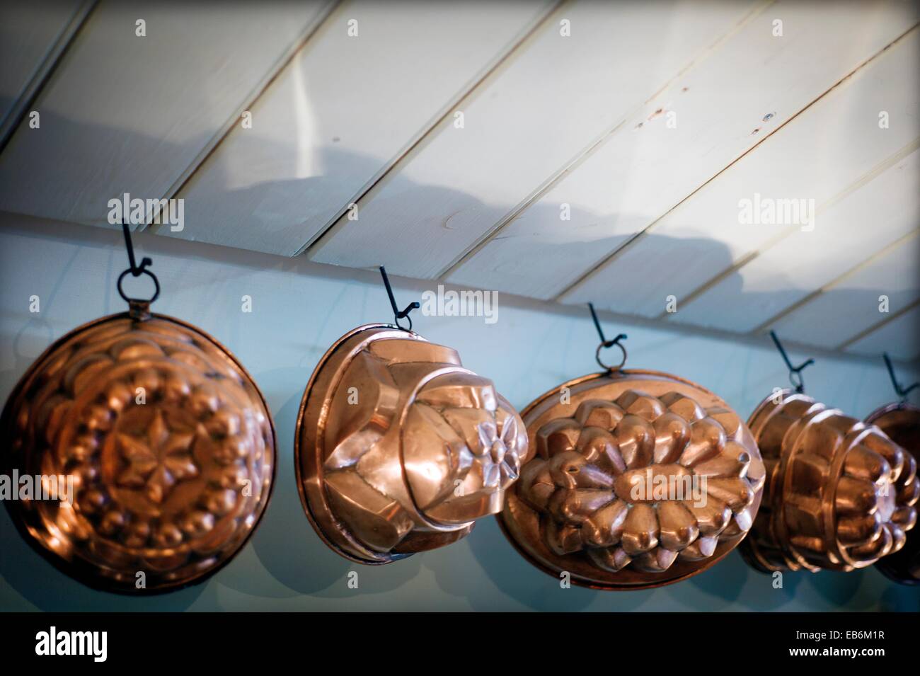 antique copper molds hanging from the ceiling in a kitchen in England