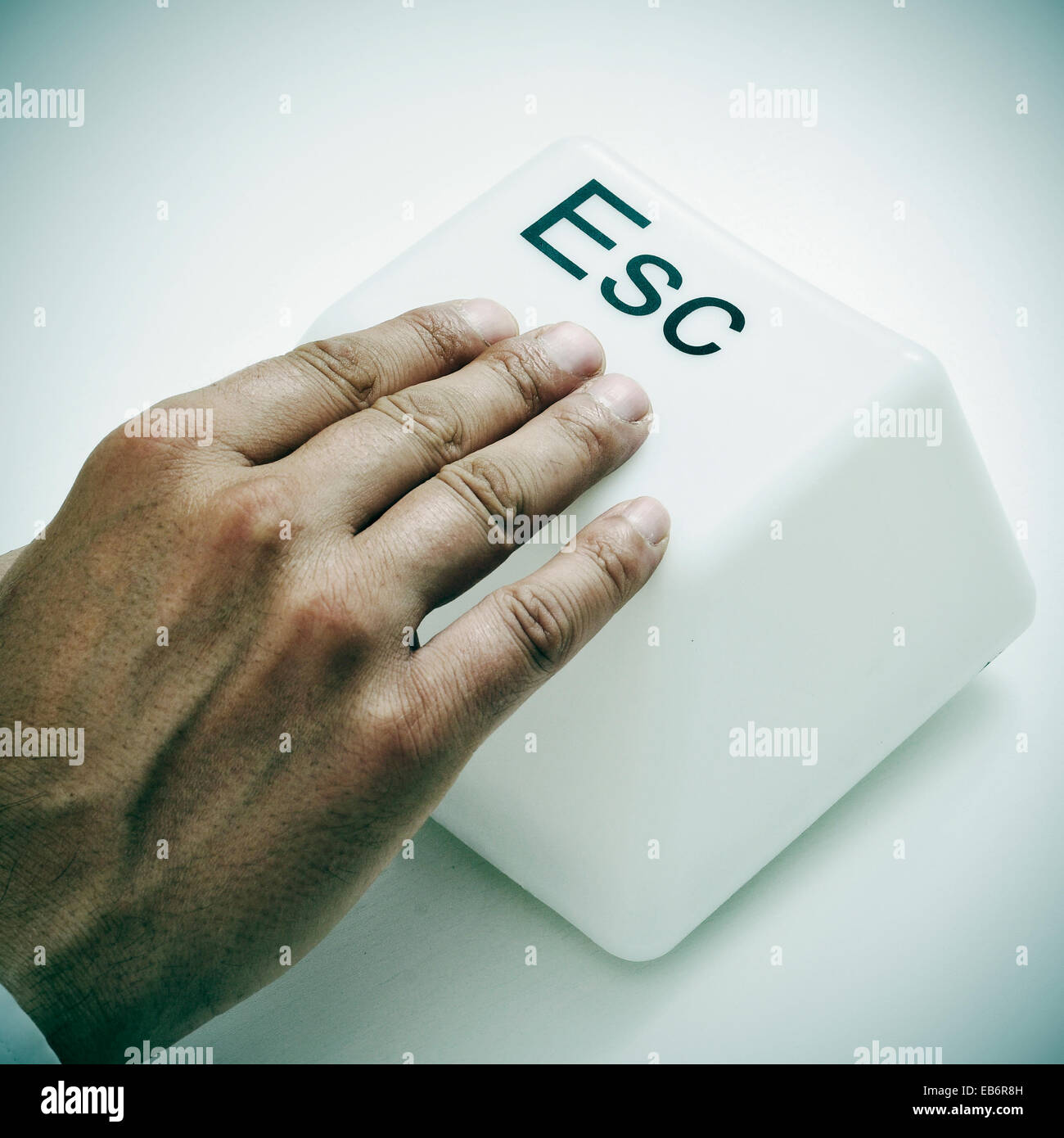 a man pressing a giant escape key with his hand Stock Photo