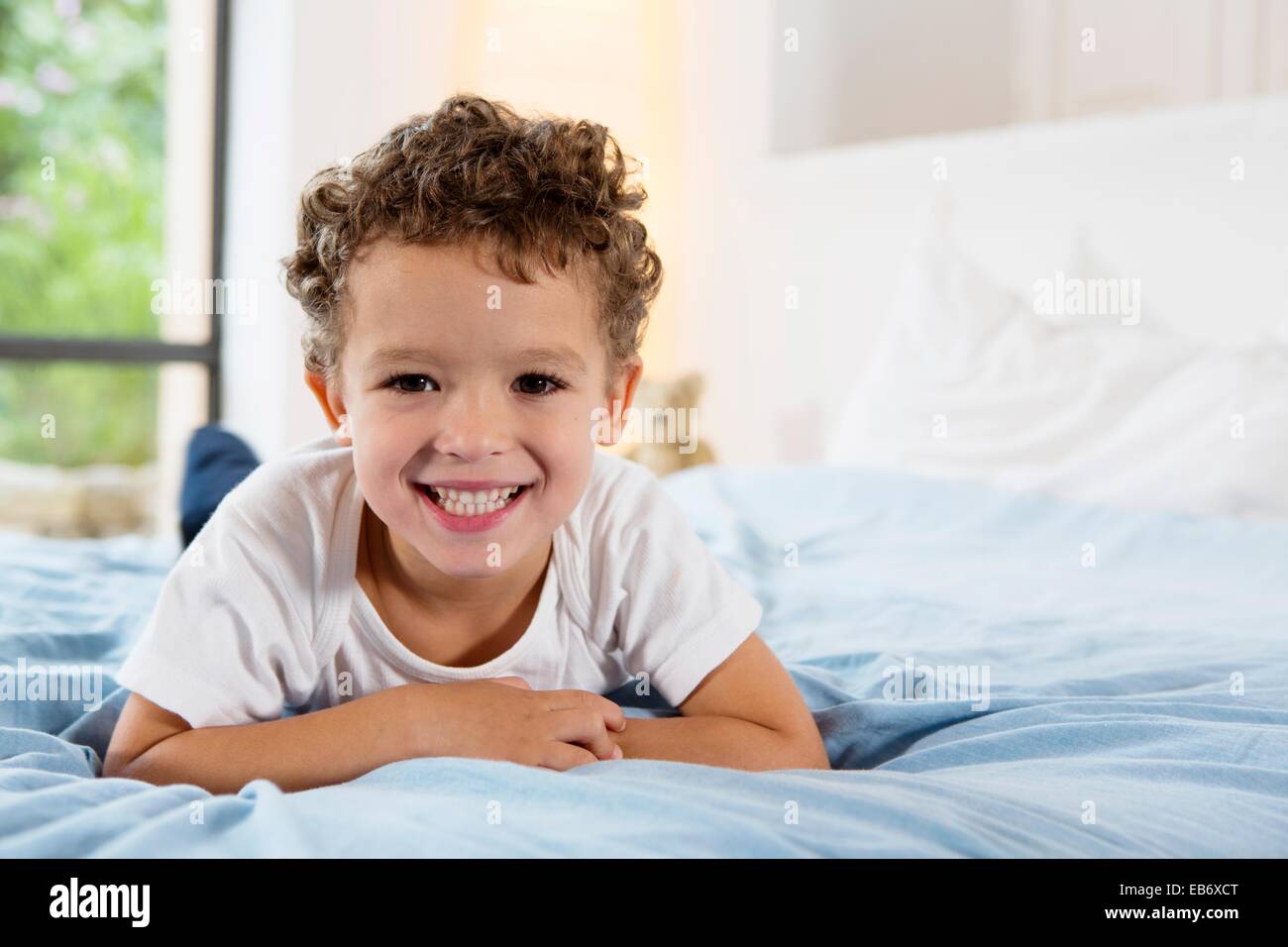 Four year old boy lying on a bed Stock Photo Alamy