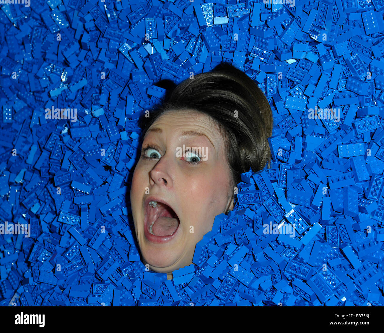 LEGO.  Alice, aged 27 from London and life long LEGO fan takes the opportunity to bury herself in a pit of blue LEGO bricks. Stock Photo