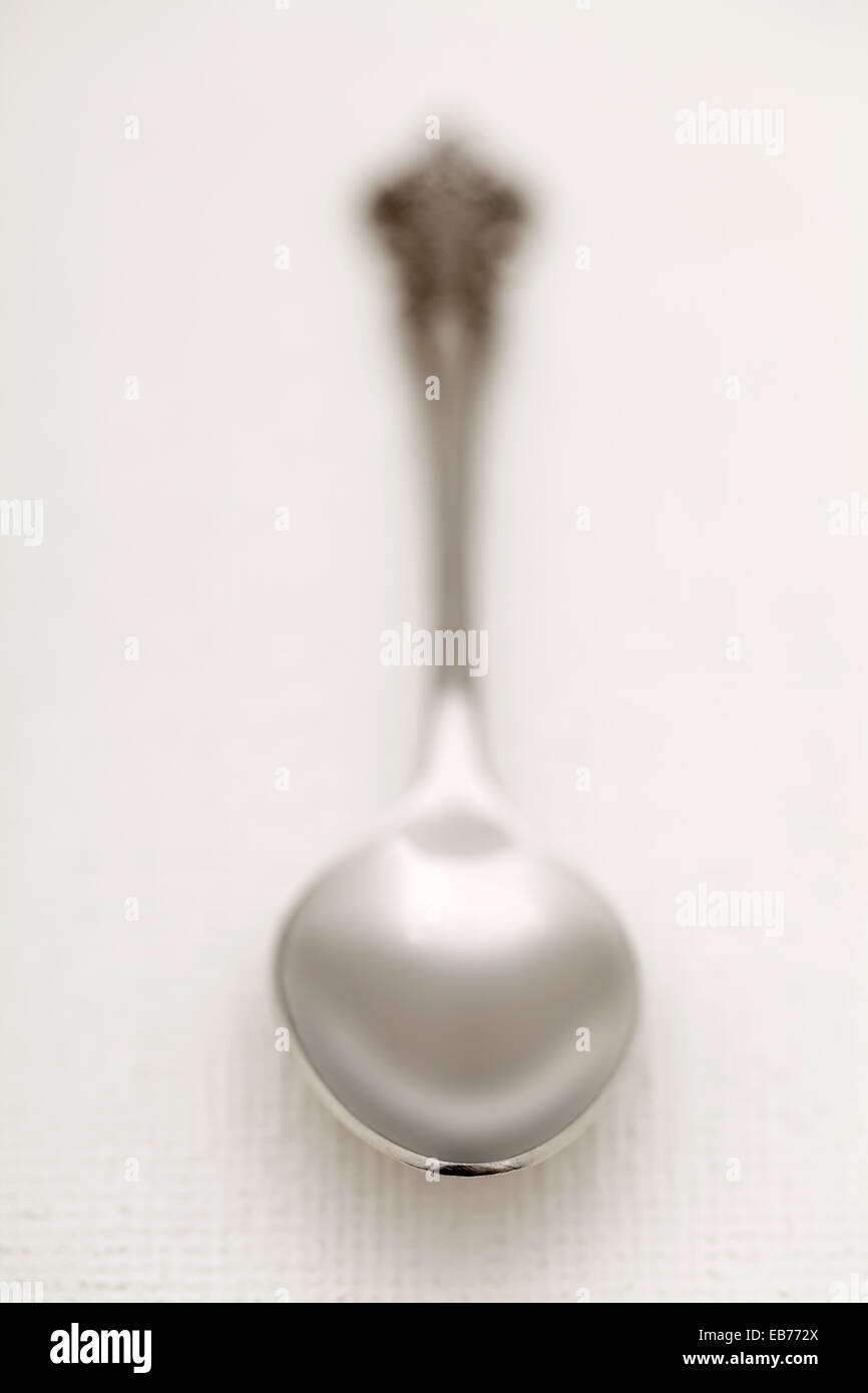 Old silver spoon with selective focus and shallow depth of field on white kitchen tablecloth Stock Photo