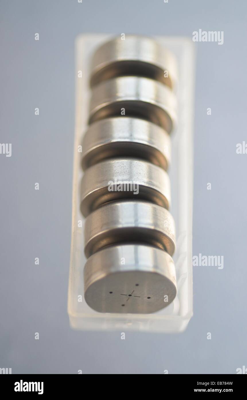 Button cells in row within a transparent plastic container. Batteries