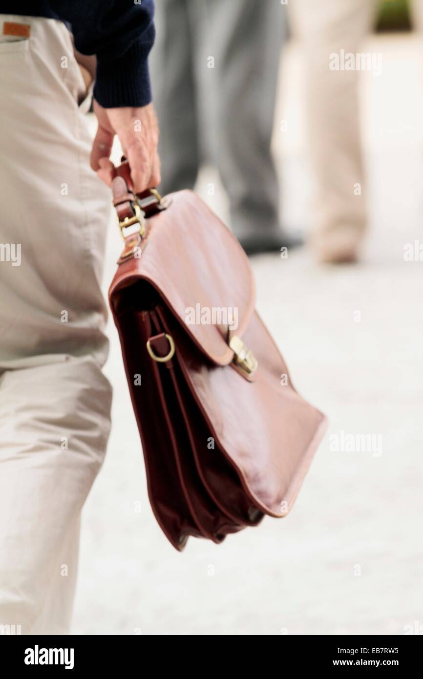 A lawyer carries the roles of a trial in a leather briefcase Stock